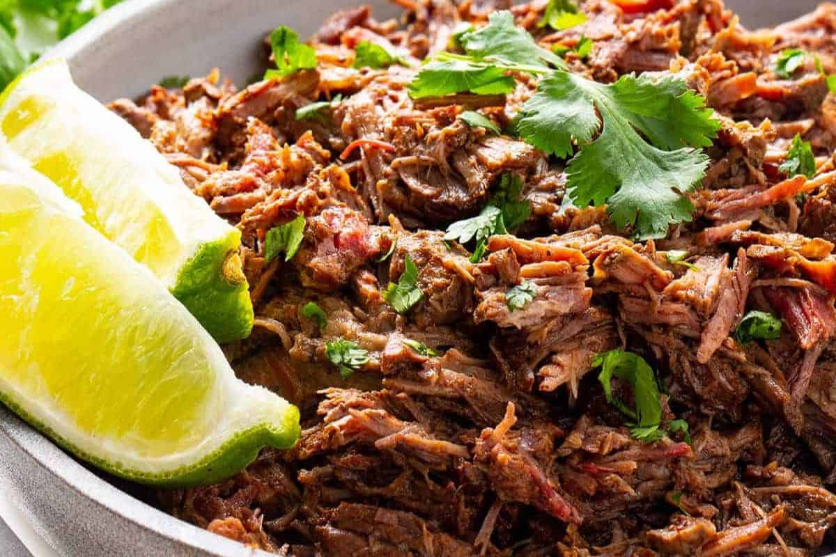 Savor a dish of shredded beef garnished with fresh cilantro and accompanied by lime wedges, inspired by your favorite Chipotle flavors.