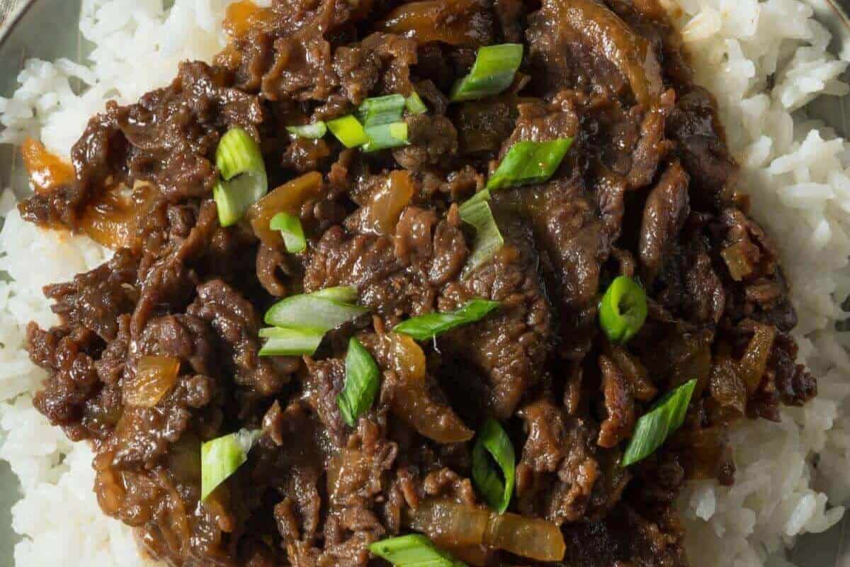 A serving of cooked beef with sliced onions and green onions on a bed of white rice—one of those Asian dishes that’s better than takeout and a must try for any food lover.