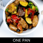 A white bowl filled with sliced apple sausage chicken, zucchini, bell peppers, and Brussels sprouts sits next to a napkin and fork.