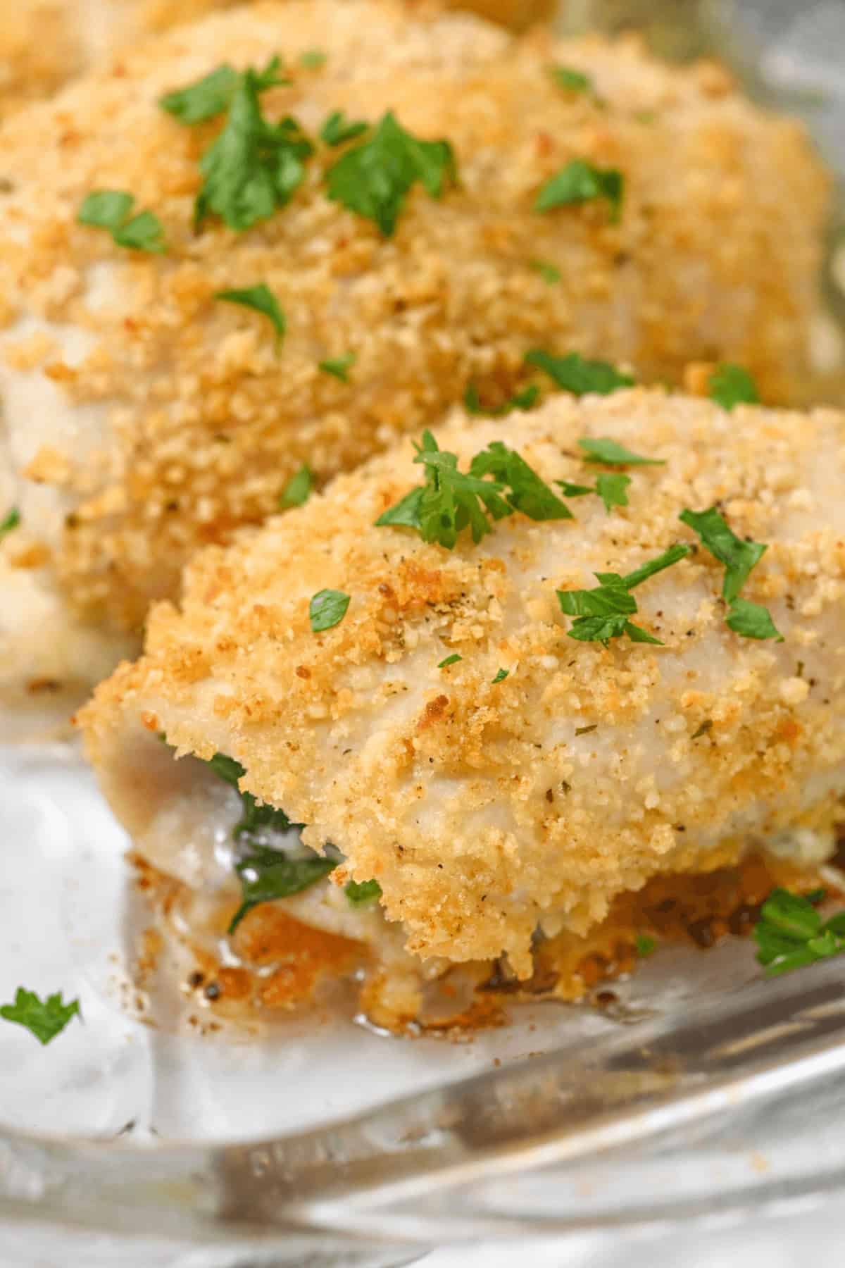 Close-up of Chicken Rollatini, elegantly garnished with chopped parsley on a clear glass dish.