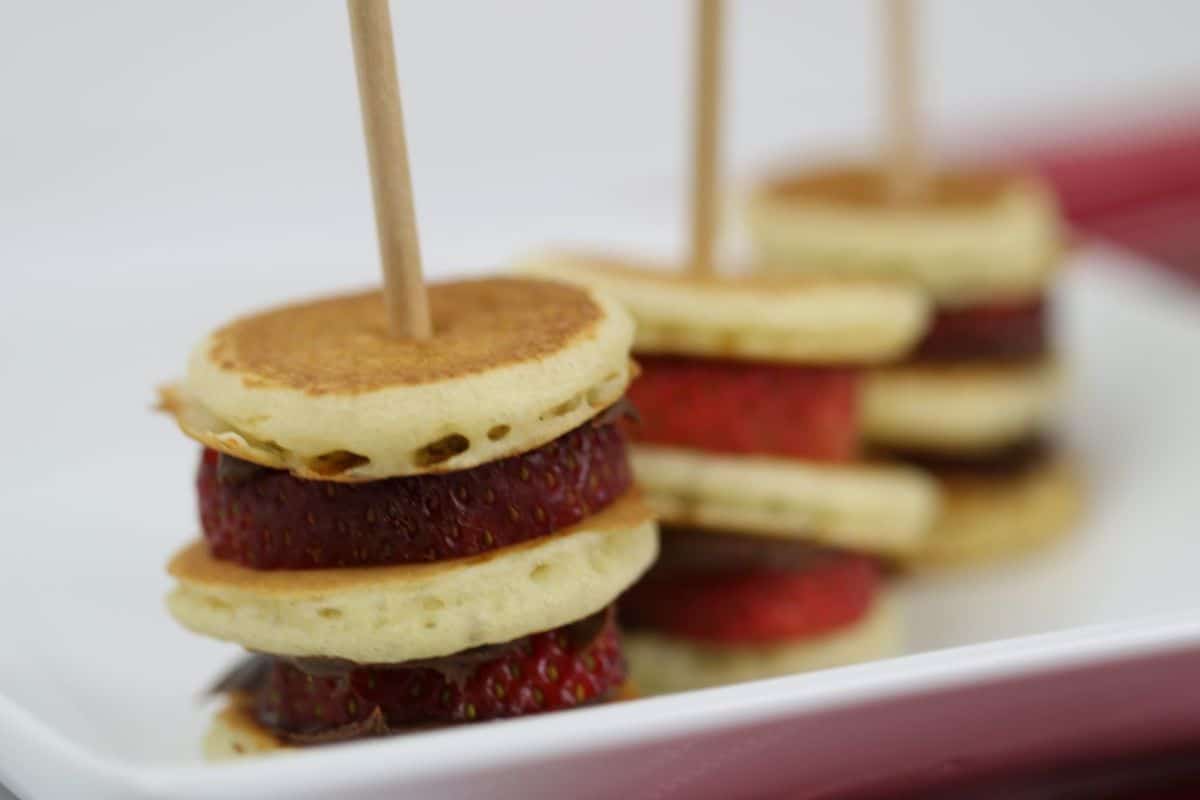 Mini pancake stacks with strawberries and skewers on a white plate make the perfect treat for a relaxing weekend brunch or to inspire new pancake recipes.