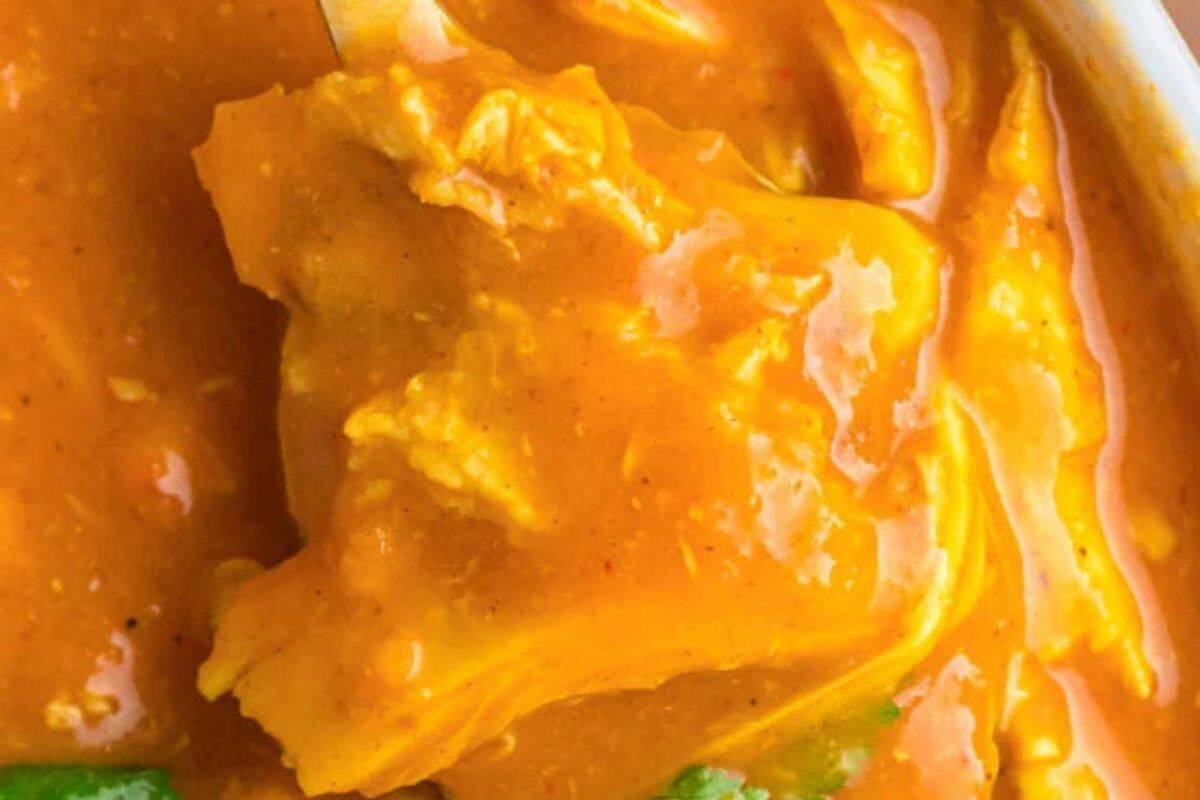 Close up of some chicken tikka masala soup on a silver spoon.