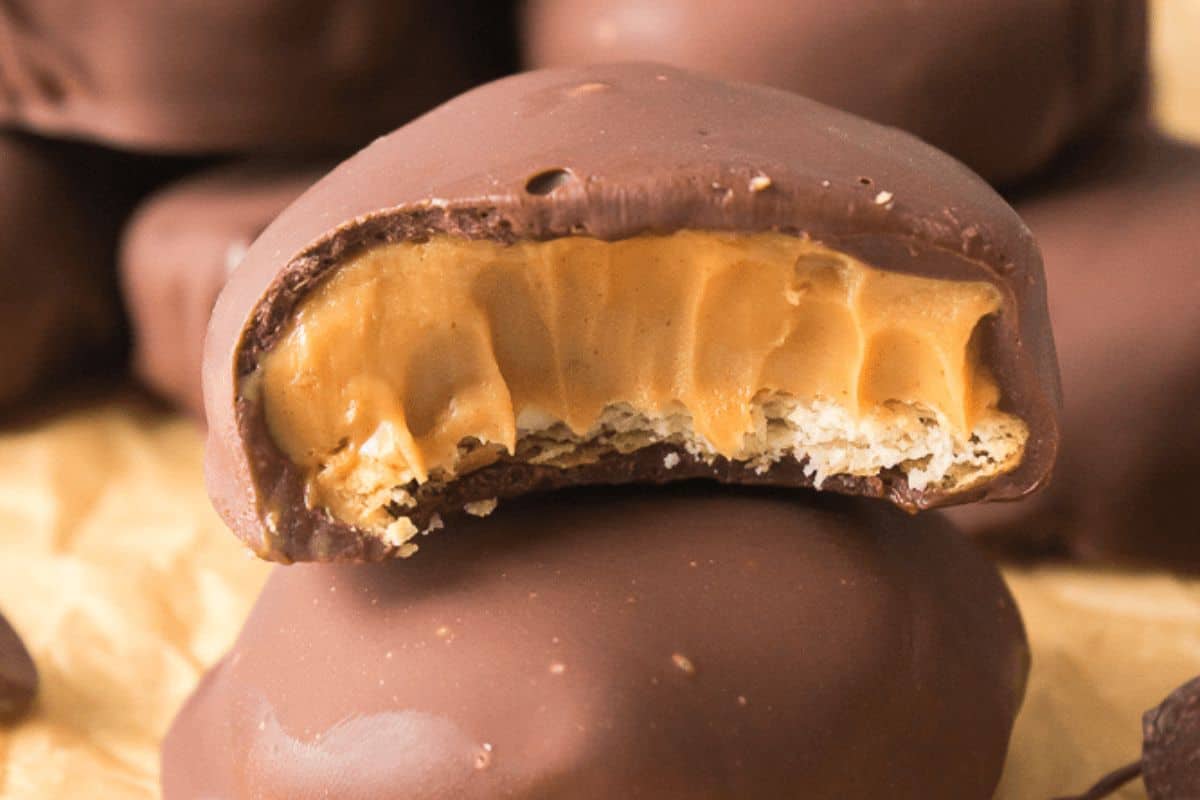 A close-up of a chocolate-covered peanut butter candy with a bite taken out, revealing the creamy peanut butter filling inside—truly one of those must-try recipes for any peanut butter enthusiast.