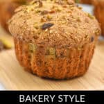 Close-up of a bakery-style pistachio muffin on a wooden board, with more delicious pistachio muffins in the background.