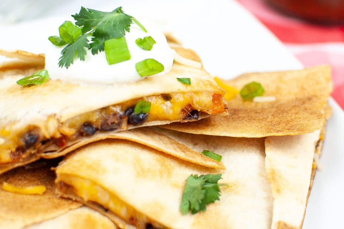 Quesadilla slices topped with sour cream, chopped green onions, and cilantro for a taste that's reminiscent of your favorite Chipotle recipes.