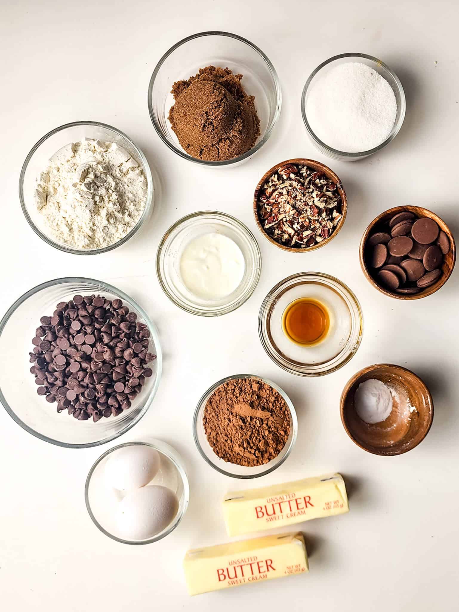 Clear glass bowls with the flour, sugar, chocolate, caramel and nuts for the snack.