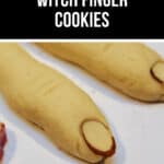 Three witch finger cookies, shaped like human fingers with almond slices as fingernails, are displayed on a white surface.