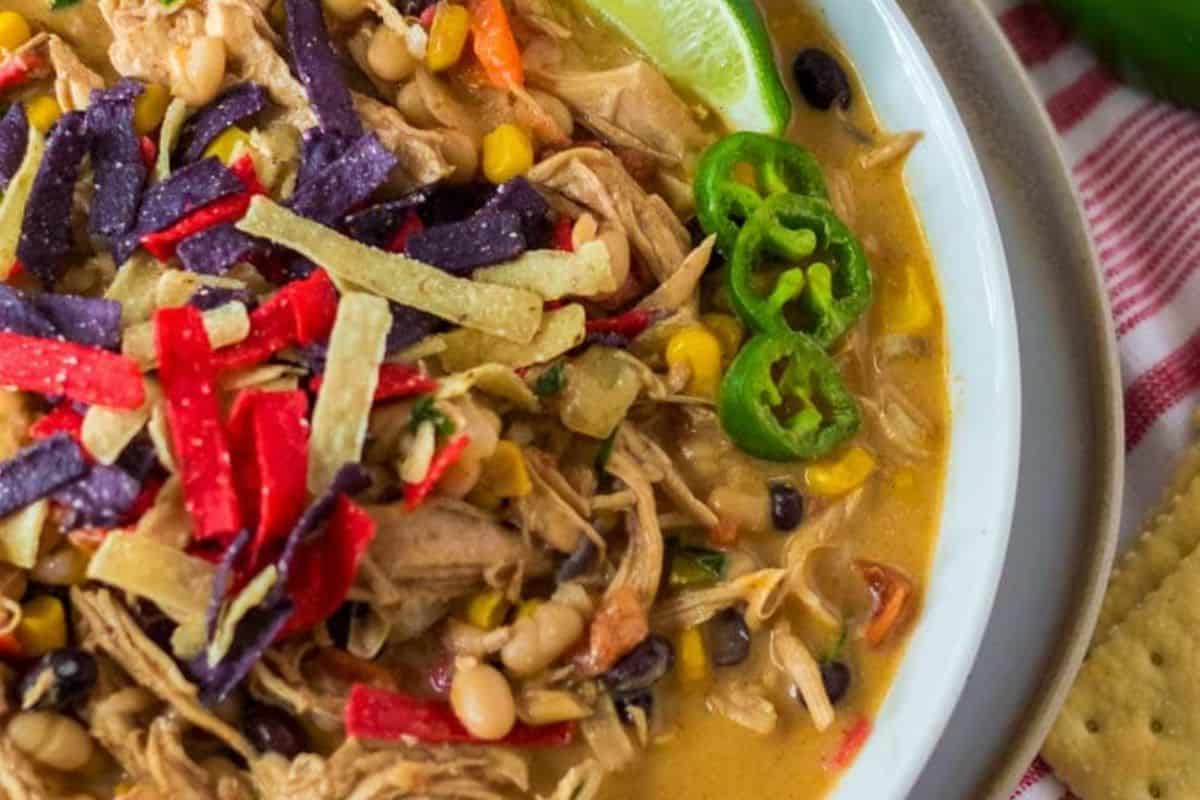 Enjoy a homemade chicken tortilla soup, reminiscent of Chick-fil-A recipes, featuring corn, black beans, and jalapeño slices. Topped with vibrant tortilla strips and served with a lime wedge for that perfect zest.