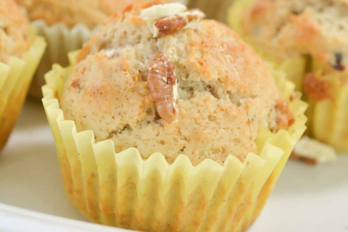 Cinnamon muffins with pecans on a white serving dish.