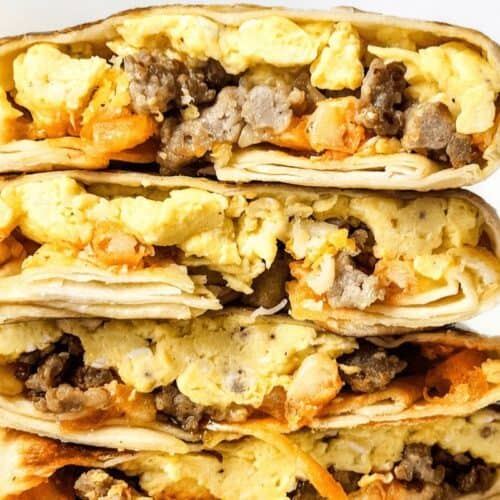 Stack of breakfast burritos filled with scrambled eggs, sausage, and cheese, cut in half to show the fillings. Perfect for those who crave quick and easy breakfast recipes.