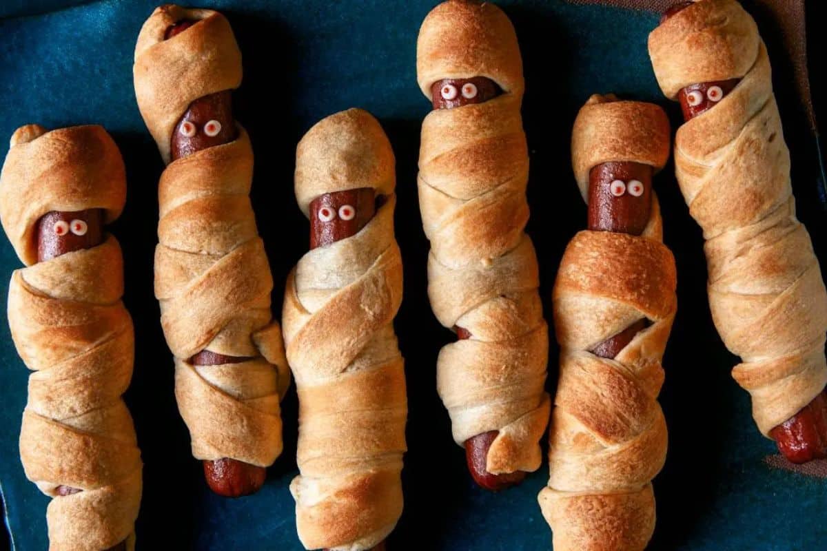 Hot dogs wrapped in crescent roll dough to look like mummies, with small edible eyes added on top.