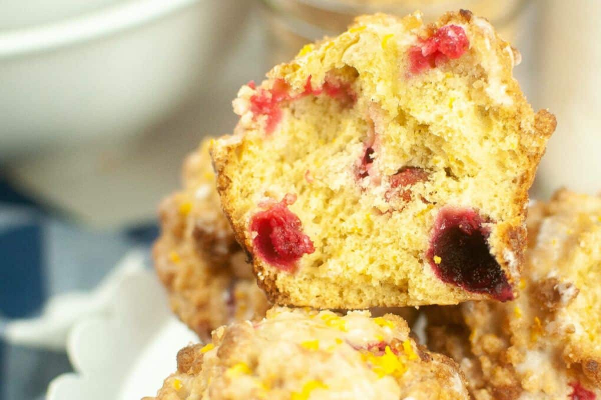 A stack of orange cranberry muffins. The top one is cut in half.