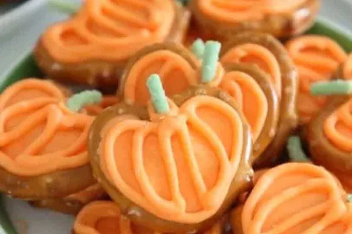  Pretzels dipped in orange chocolate with green chocolate stems, decorated to look like miniature pumpkins.