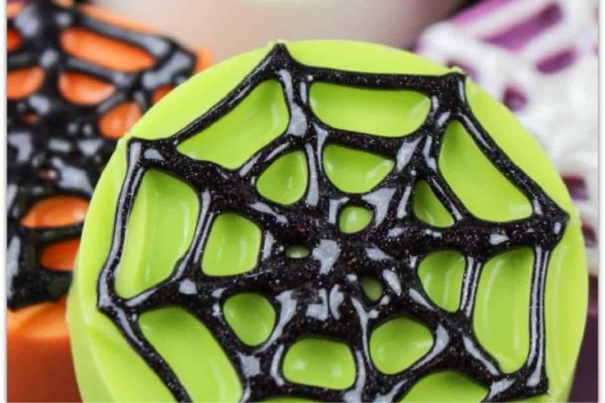 Chocolate-covered Oreos decorated with drizzle in a spider web pattern.
