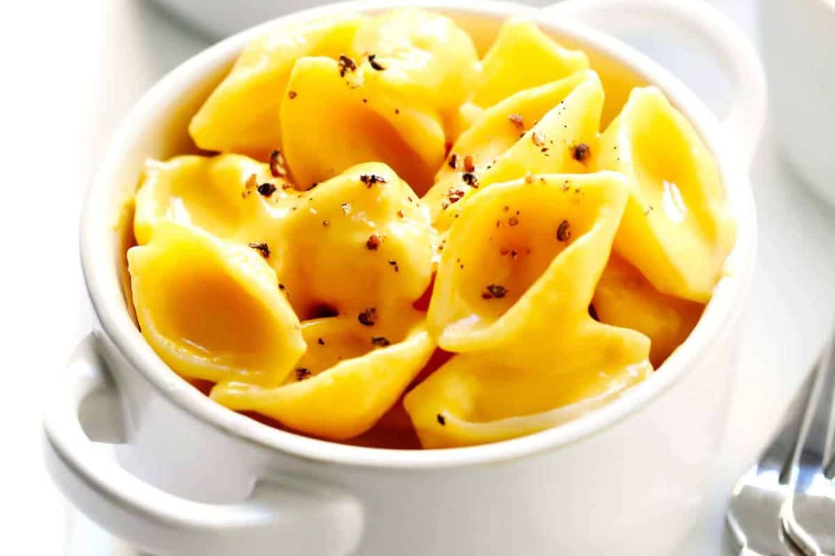 A white bowl filled with macaroni and cheese, topped with cracked black pepper—a perfect choice for comforting fall meals.