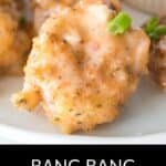 Close-up of Bang Bang Shrimp: crispy breaded shrimp coated in a creamy sauce, garnished with chopped green onions, served on a white plate. Text at bottom reads "Bang Bang Shrimp.