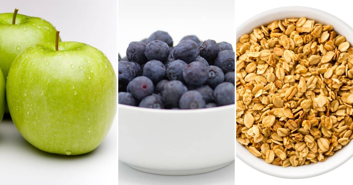 Green apples and blueberries in a white bowl, alongside granola in another white bowl, are displayed side by side against a white background.
