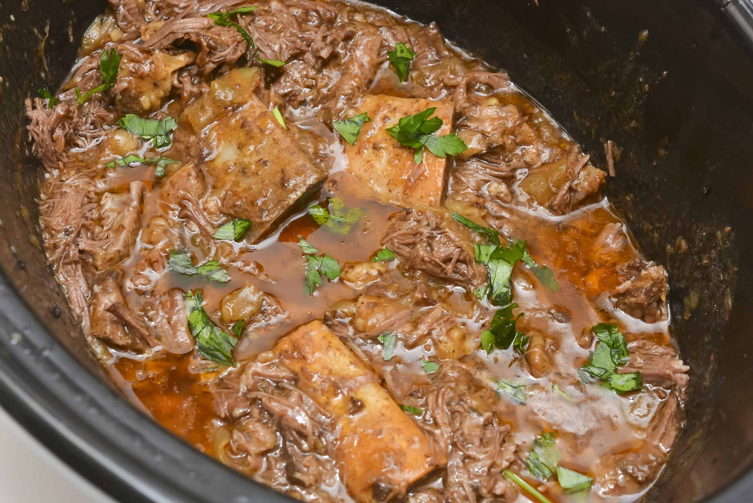 Sow-cooked in a rich brown sauce with chopped parsley, served hot in a black slow cooker.