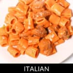 A delectable plate of Italian pork sausage pasta, smothered in a creamy sauce and elegantly garnished with fresh parsley, sits enticingly on a pristine white dish.