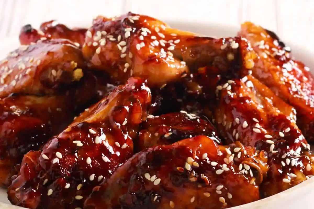 Plate of glazed chicken wings sprinkled with sesame seeds.