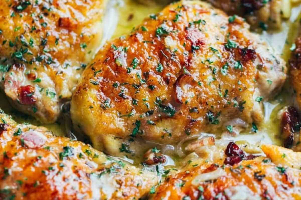 Close-up of baked chicken thighs topped with herbs and a golden, glazed sauce—perfect for your collection of cast iron recipes.