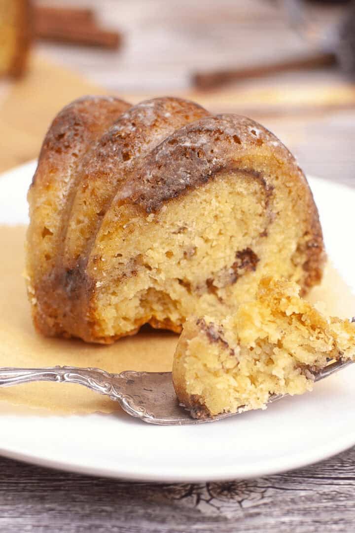 A slice of marble bundt coffee cake rests elegantly on a white plate, accompanied by a polished fork.