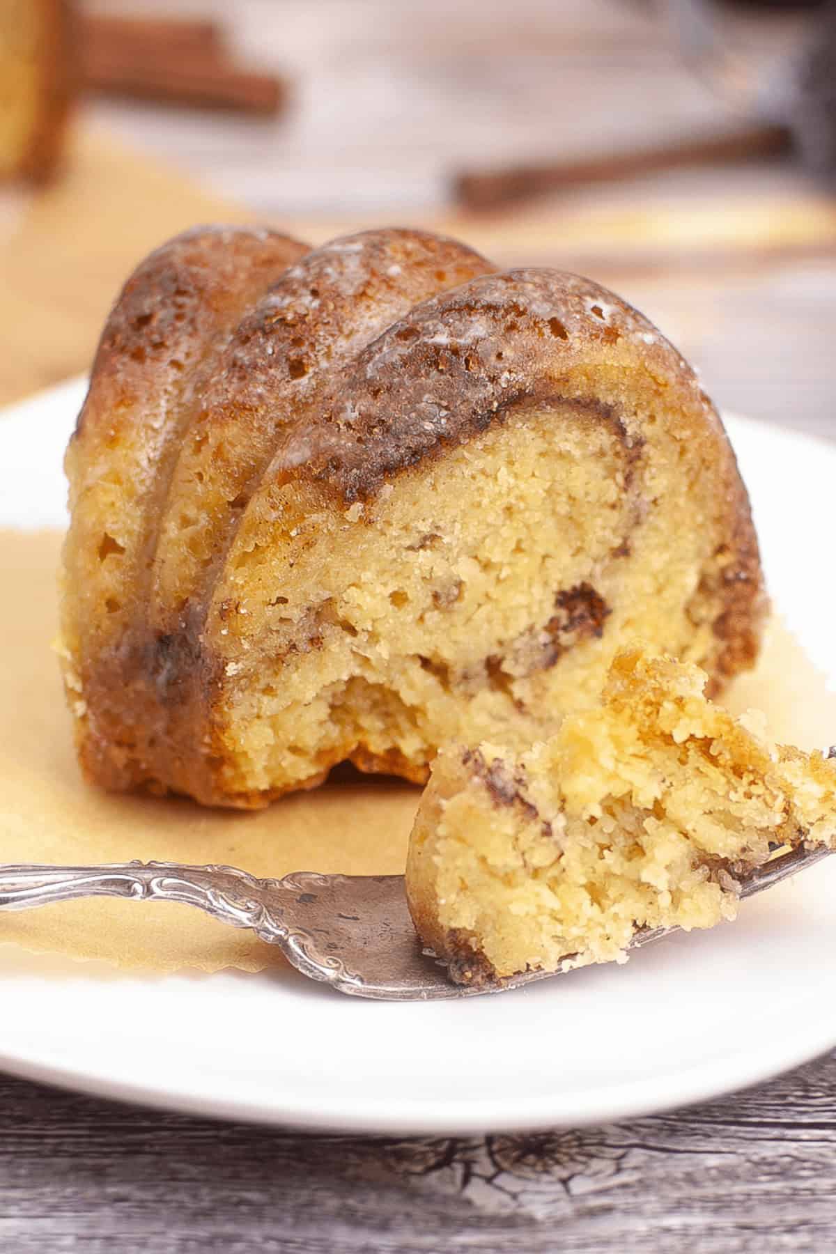 A slice of marble bundt coffee cake rests elegantly on a white plate, accompanied by a polished fork.