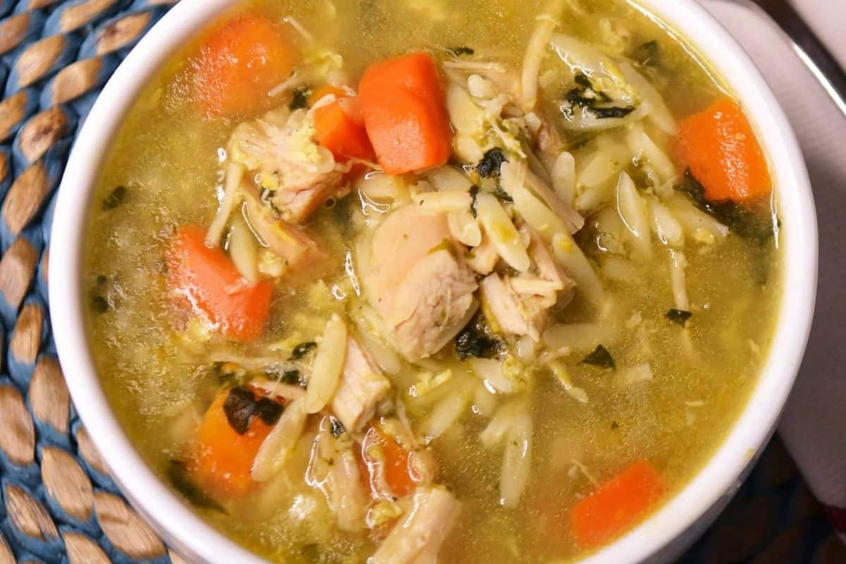 Close-up of some turkey orzo soup, with carrots and orzo noodles.