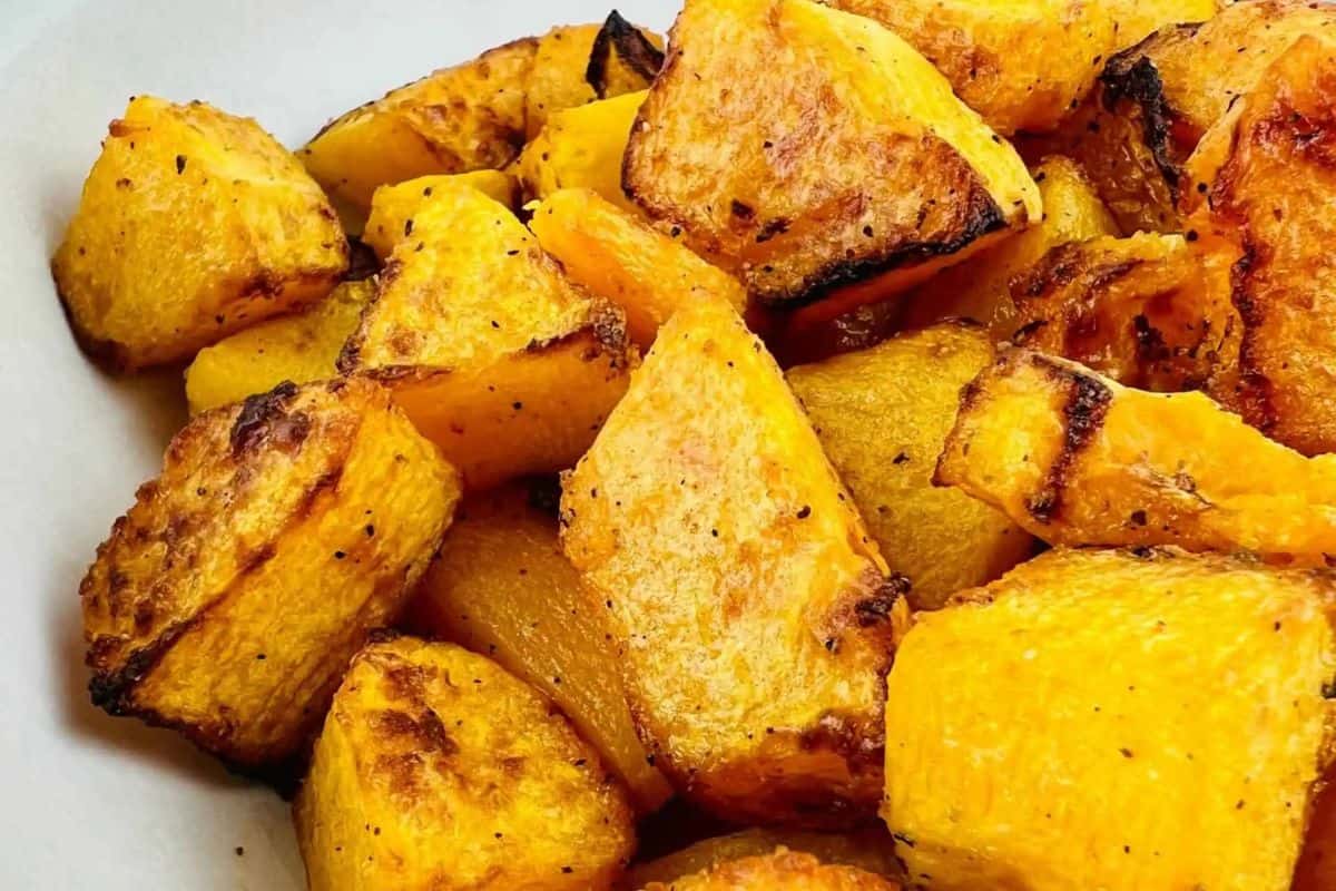 Close-up of roasted butternut squash cubes with a golden-brown, slightly charred surface, seasoned with black pepper—a delicious addition to your favorite squash recipes.
