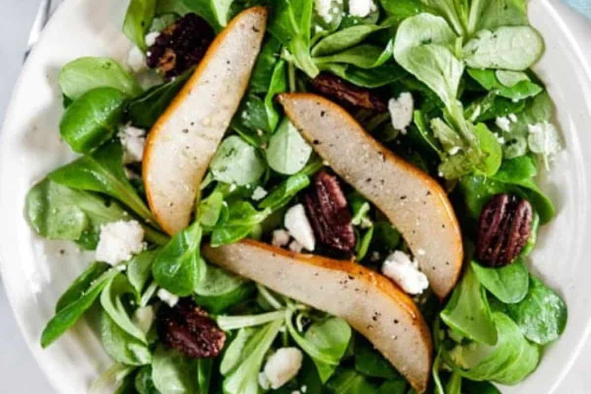 Winter salad with roast pears and vanilla vinaigrette in a white bowl.