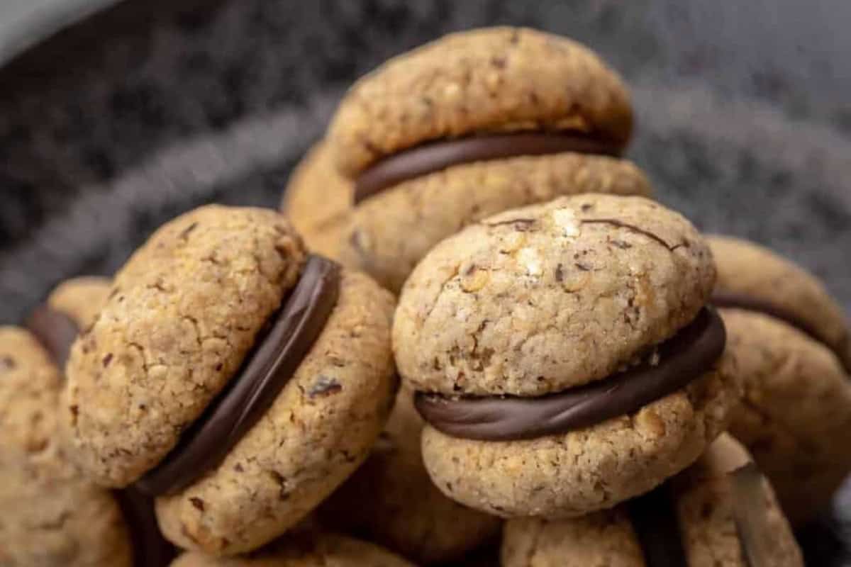 A close-up of several roasted hazelnut sandwich cookies with chocolate filling.
