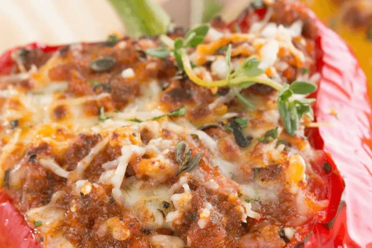 Close-up of a stuffed red bell pepper topped with melted cheese, ground meat, herbs, and a sprig of fresh thyme—perfect for easy stuffed peppers or weeknight dinner inspiration.