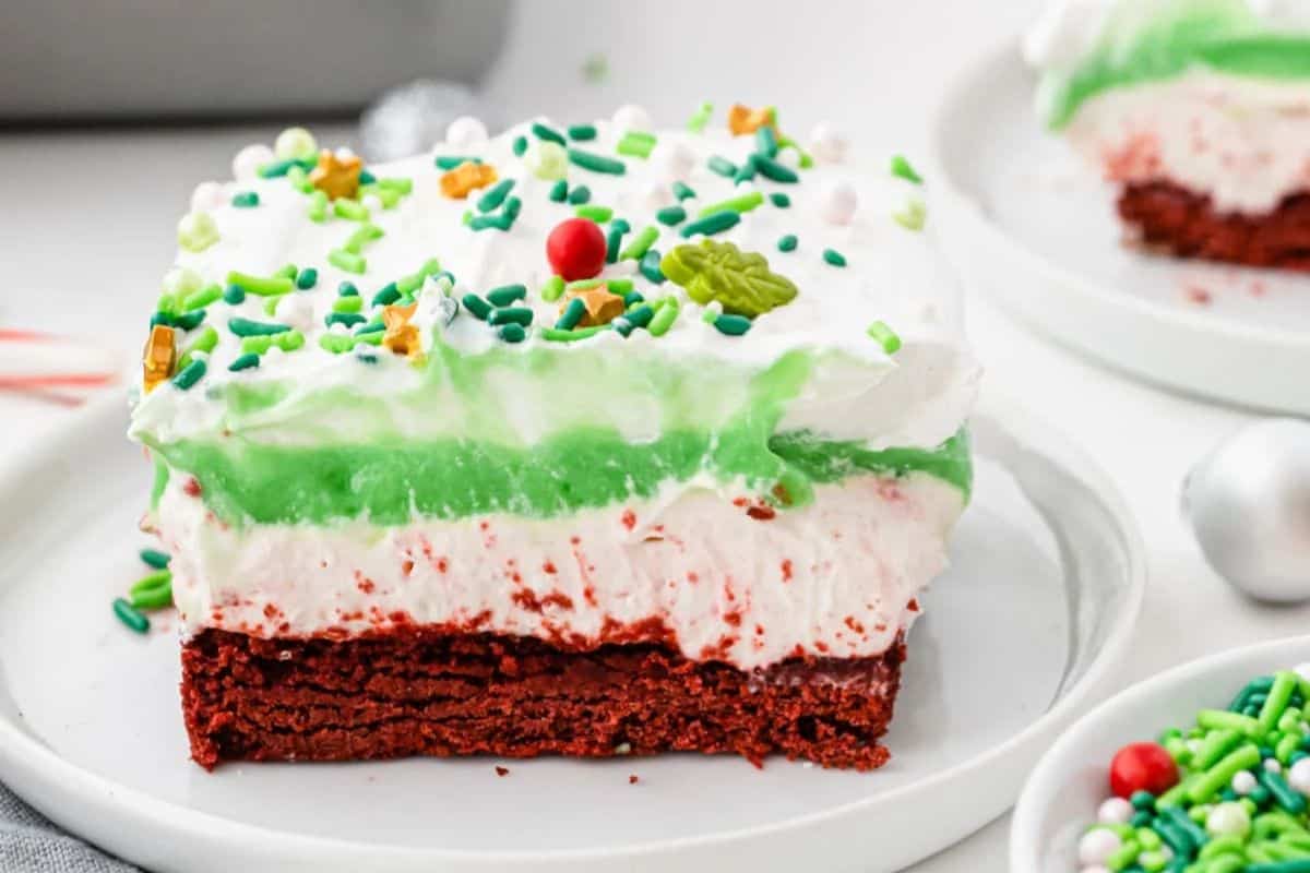 Layered dessert with crushed cookies, whipped topping, and red and green sprinkles.