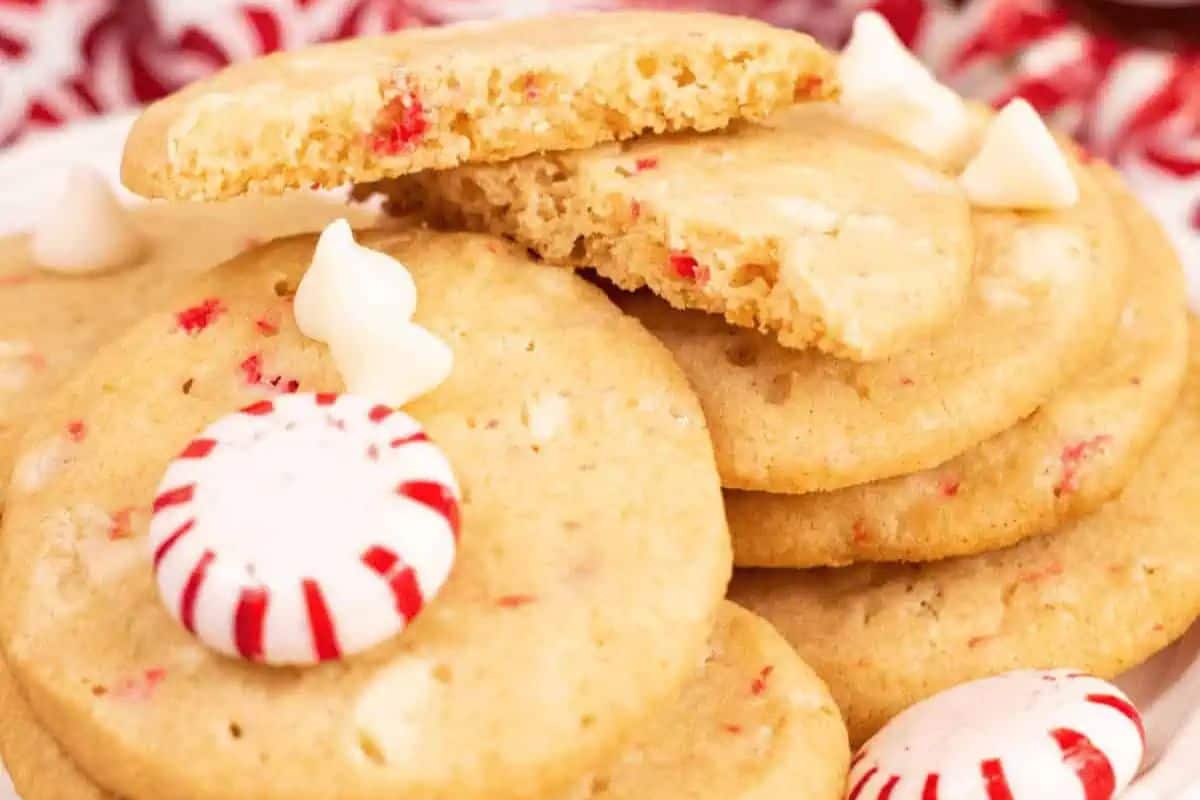 Soft peppermint cookies topped with crushed candy canes and white chocolate chips on a white plate, perfect for holiday baking.