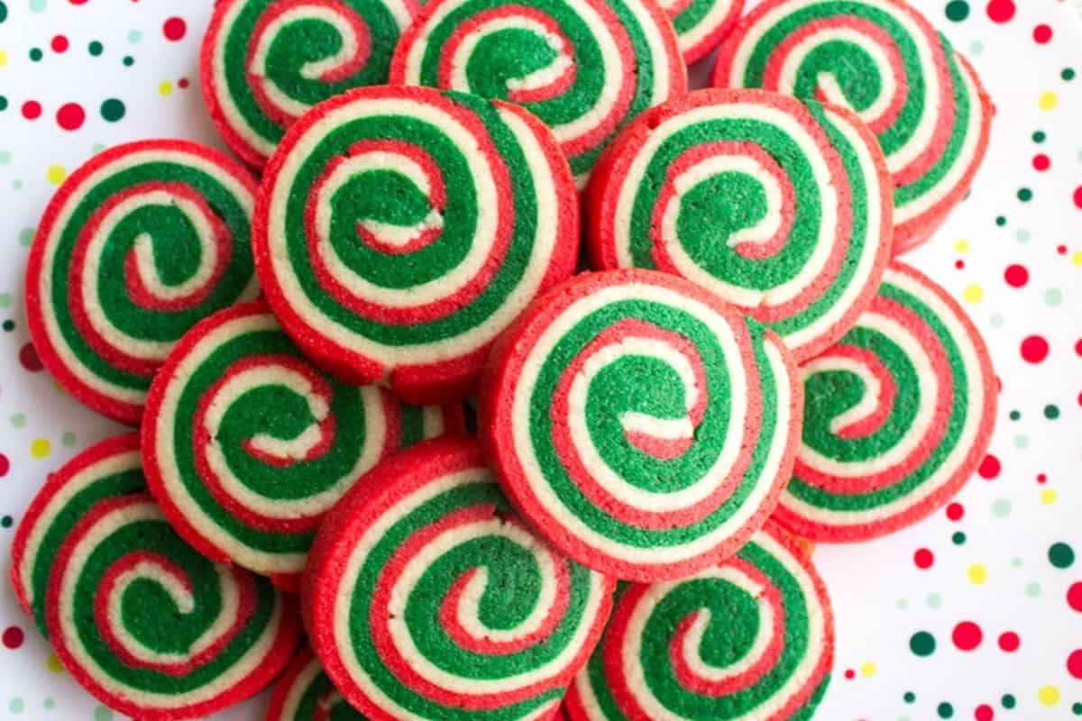 Bright red and green pinwheel sugar cookies with swirled designs, displayed on a cookie tray.
