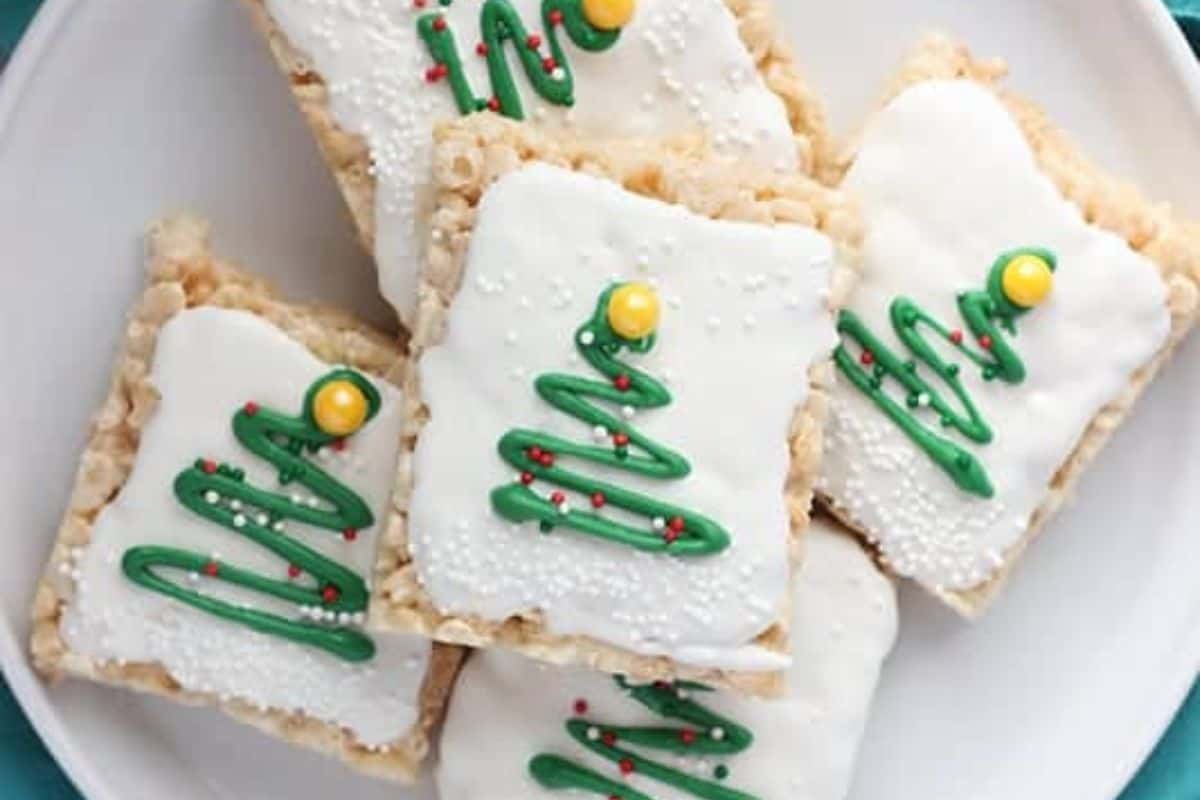 Rice Krispe treats with white icing and green icing swirled to look like trees, served on a white plate.