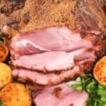 A crispy brown crust on the meat, is elegantly garnished with grilled orange slices and fresh parsley.