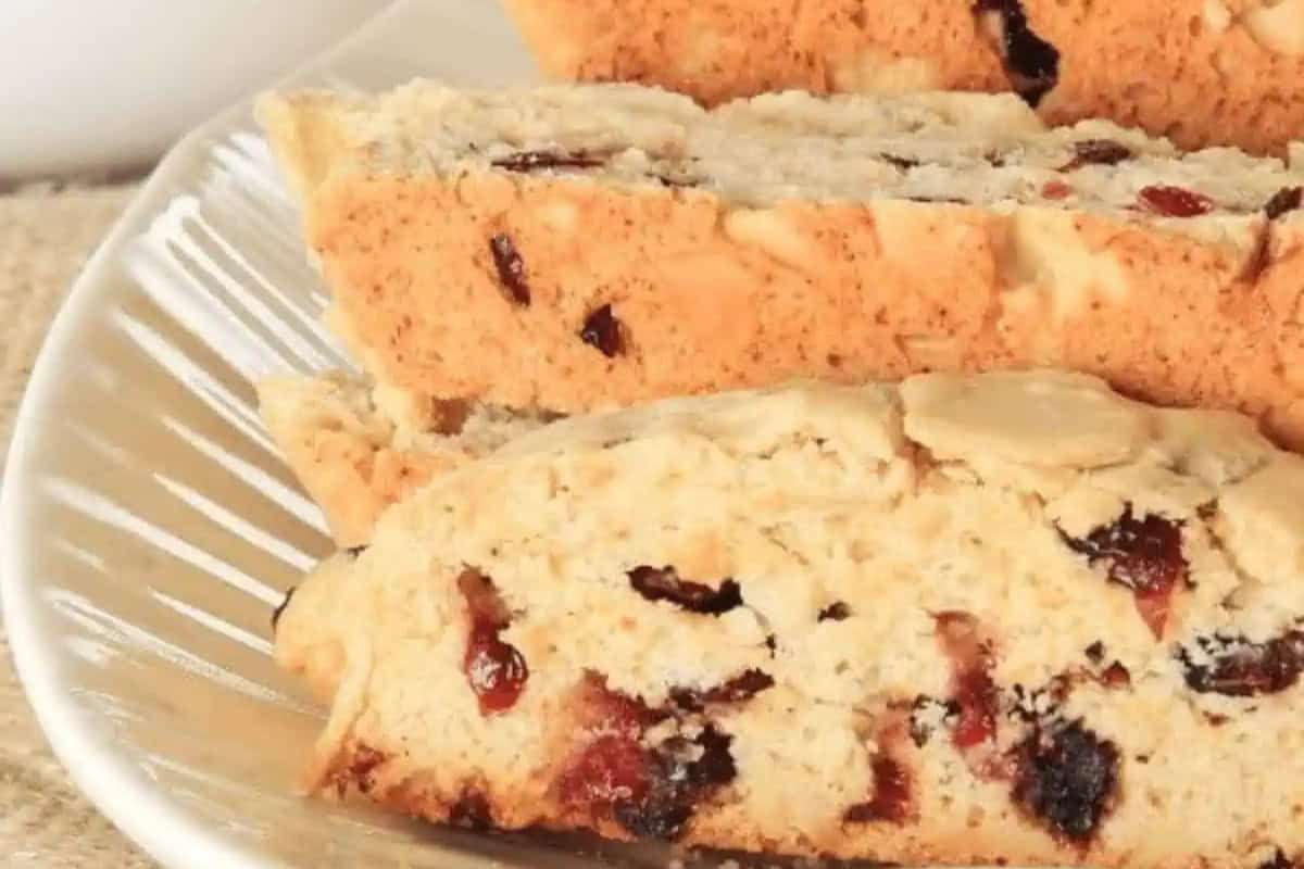 Three slices of biscotti with visible dried cranberry pieces are arranged on a white plate.