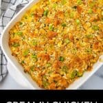 A baked Creamy Chicken Noodle Casserole topped with crushed crackers and sliced green onions sits in a white dish beside a checkered towel, ready to serve.