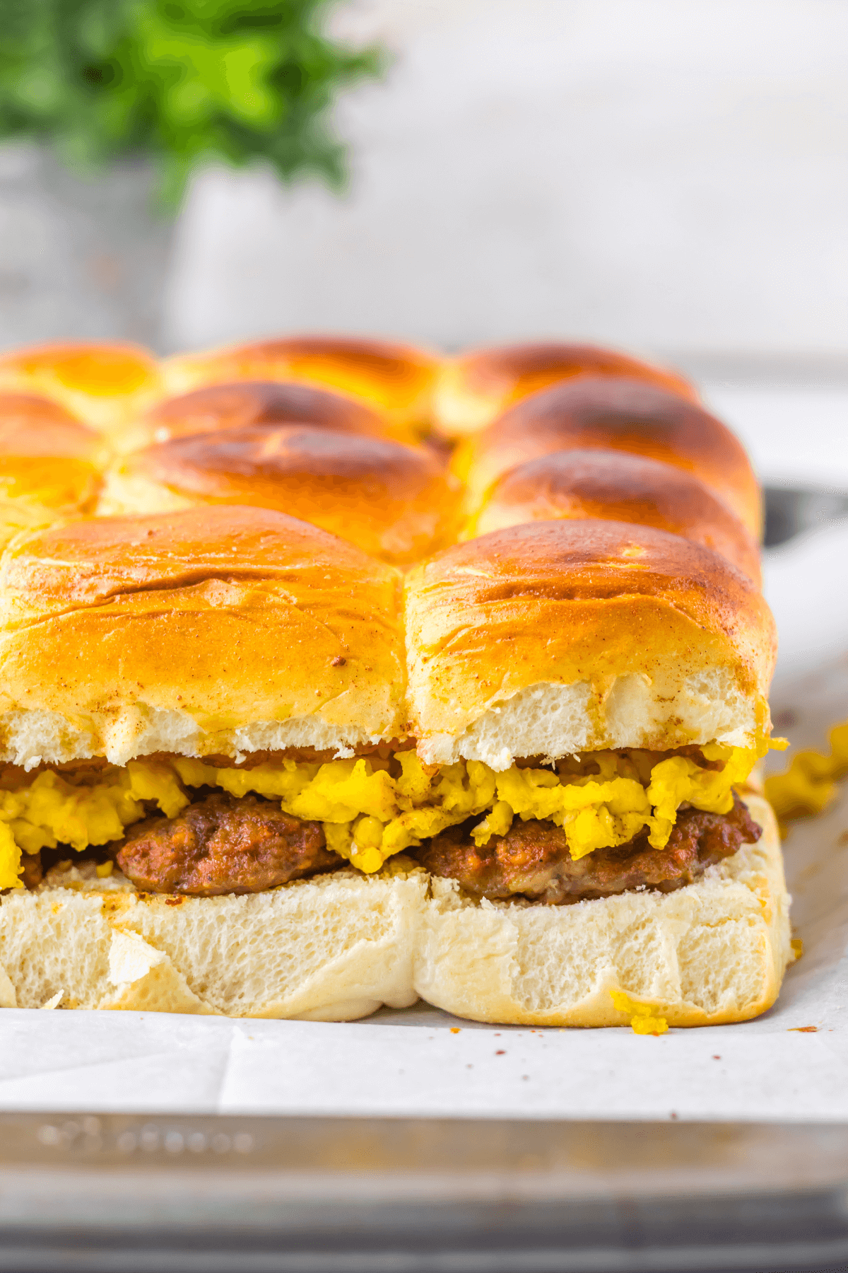 A close-up of delicious sandwicb showcases sandwiches filled with scrambled eggs and sausage, artfully arranged on parchment paper.