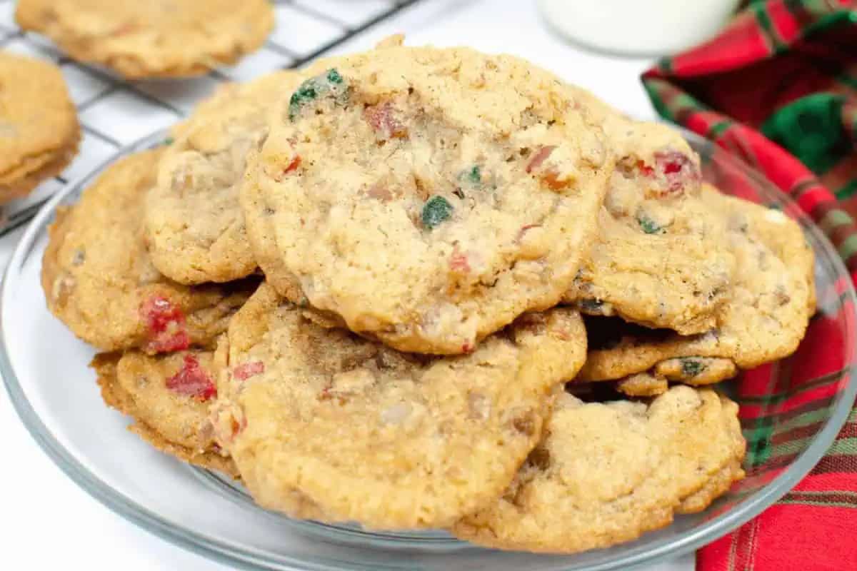 A plate of chewy Christmas Cookies with red and green candied fruit pieces sits on a table next to a red and green cloth napkin