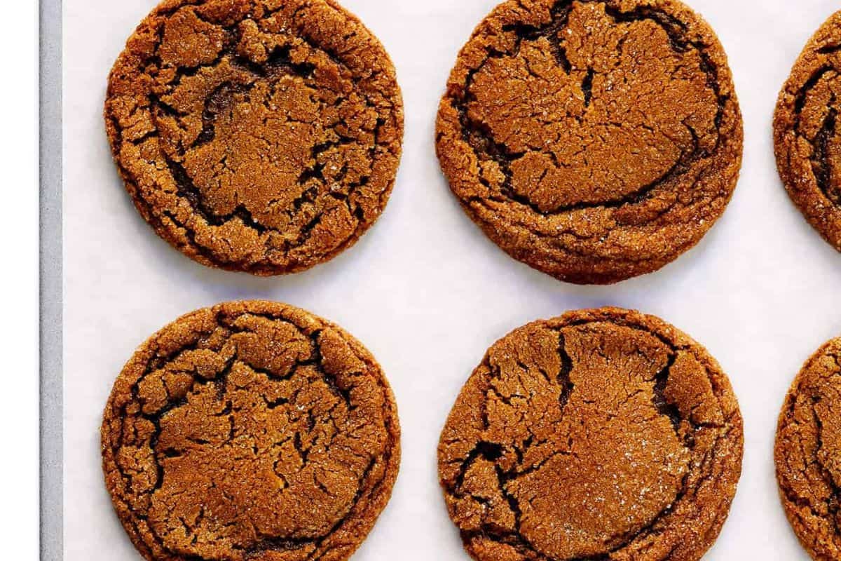 Soft and chewy ginger molasses cookies with crackly tops, arranged on a baking sheet.