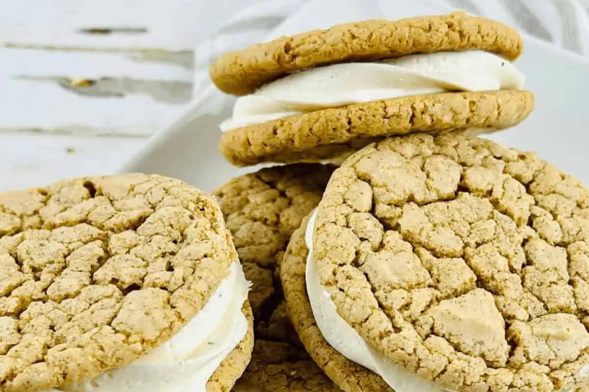 Four Gingerbread Sugar Cookies with Eggnog Frosting are stacked and arranged on a white surface