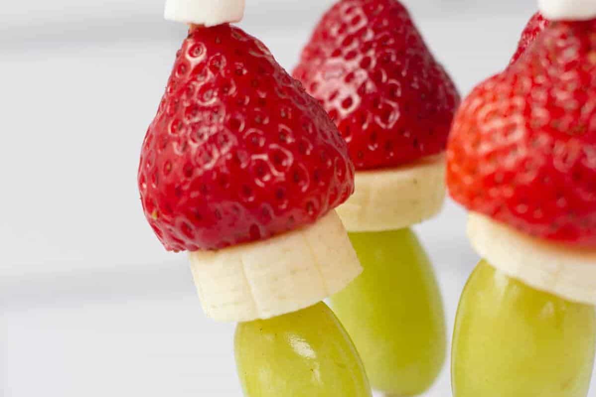 Skewers with green grapes, banana slices, and strawberries stacked to resemble the Grinch’s hat.