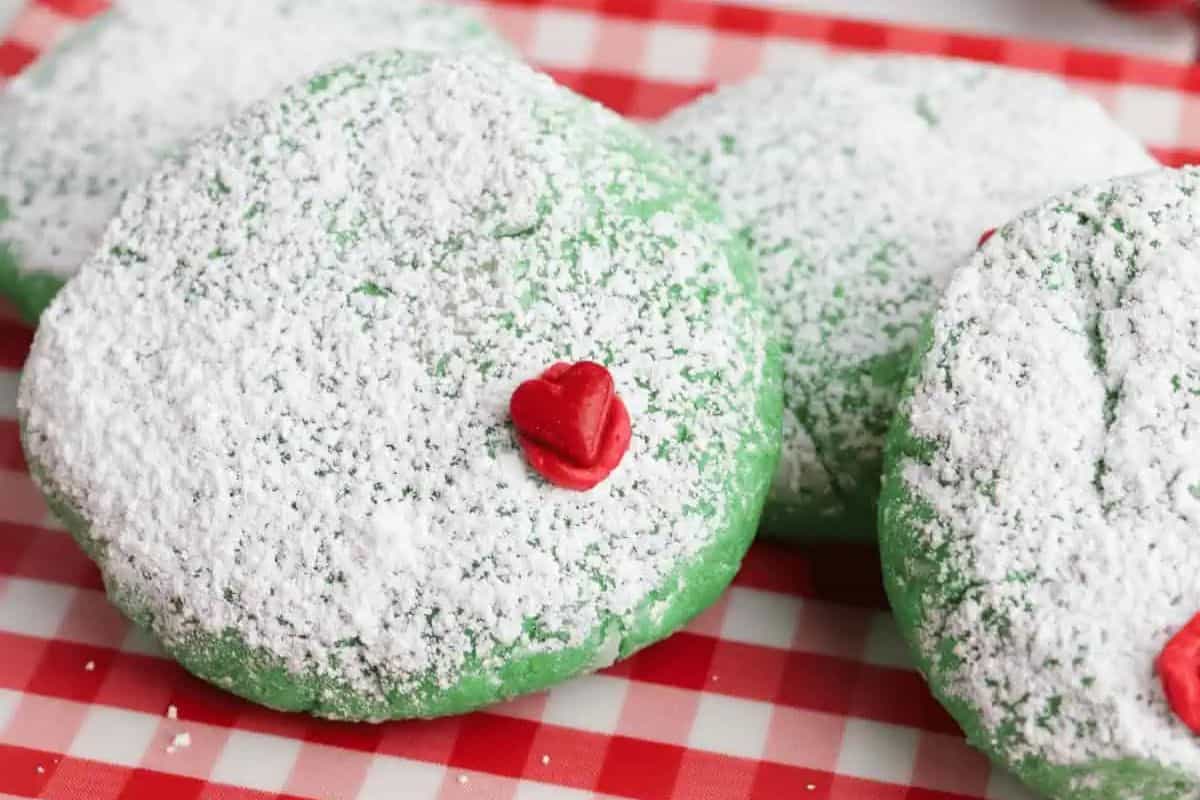 Soft, round green cookies with cracked tops and red heart sprinkles.