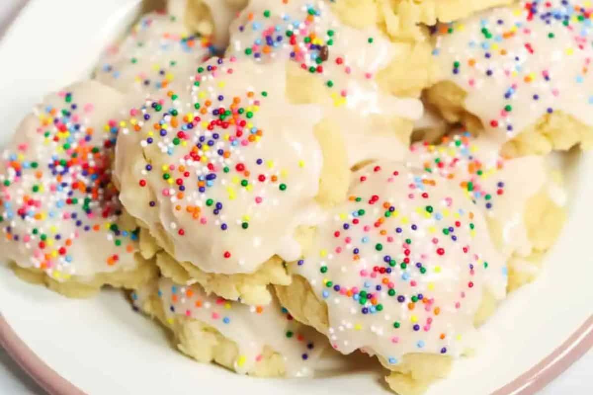 A plate of lemon ricotta holiday cookies topped with multicolored round sprinkles, perfect for any festive celebration.