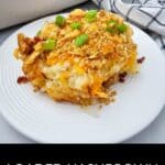 A serving of loaded hashbrown casserole, inspired by the comfort of Creamy Chicken Noodle Casserole, is topped with crushed chips and green onions on a white plate, with a baking dish and checkered towel in the background.
