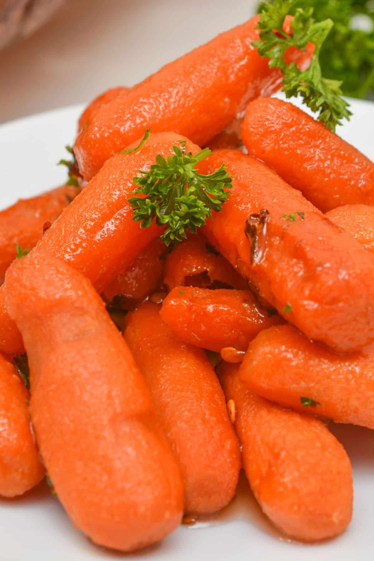A plate of Maple glazed carrots garnished with parsley and a light glaze, arranged closely together on a white surface.