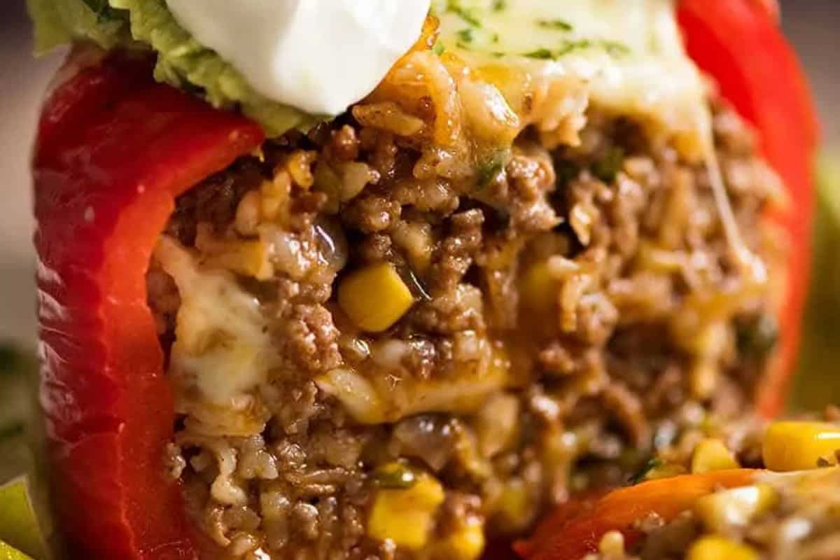 A close-up of easy stuffed peppers filled with ground meat, rice, corn, melted cheese, and topped with avocado and sour cream—perfect for effortless weeknight dinners.