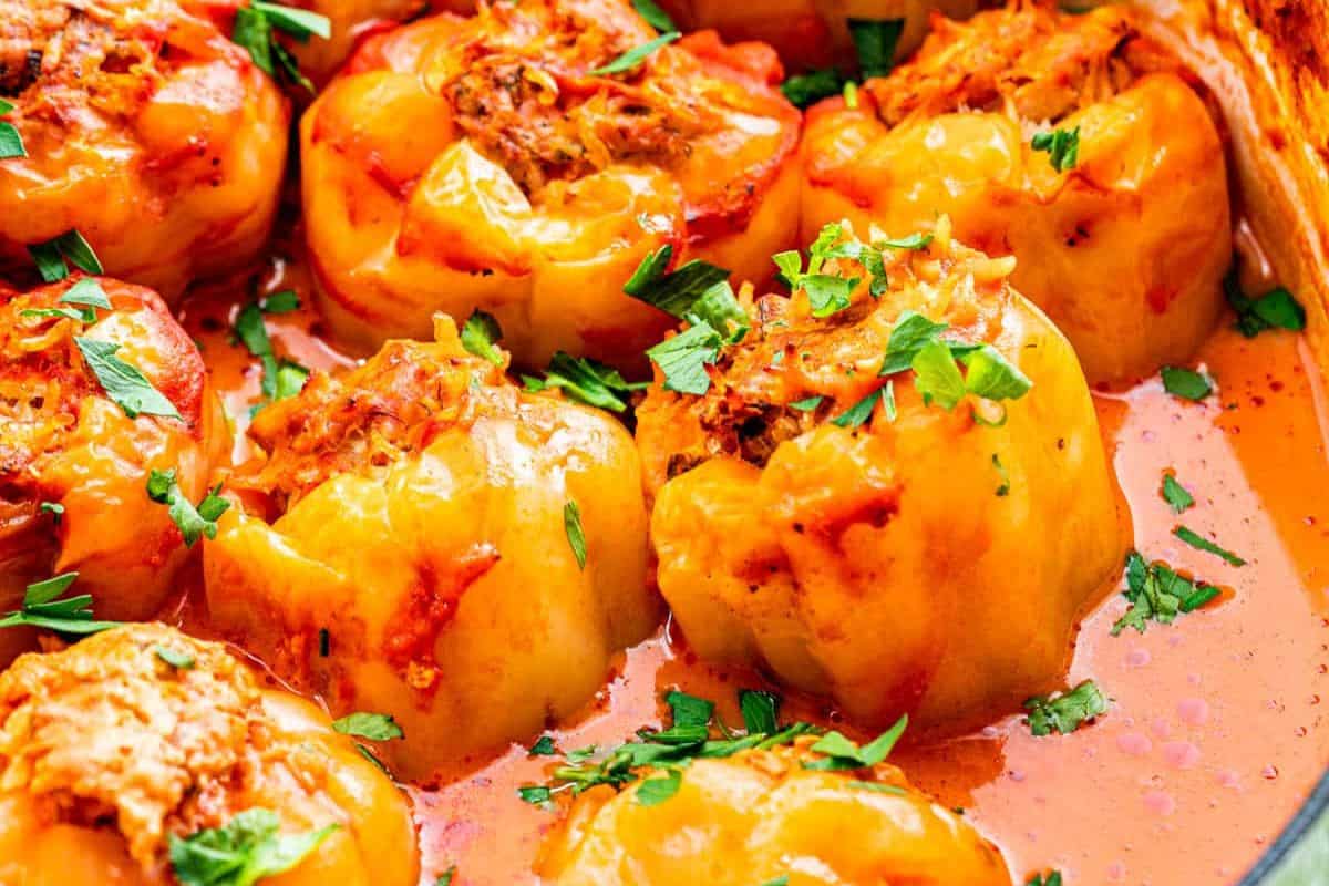 Close-up of easy stuffed peppers in a tomato-based sauce, garnished with chopped fresh herbs—perfect for delicious weeknight dinners.